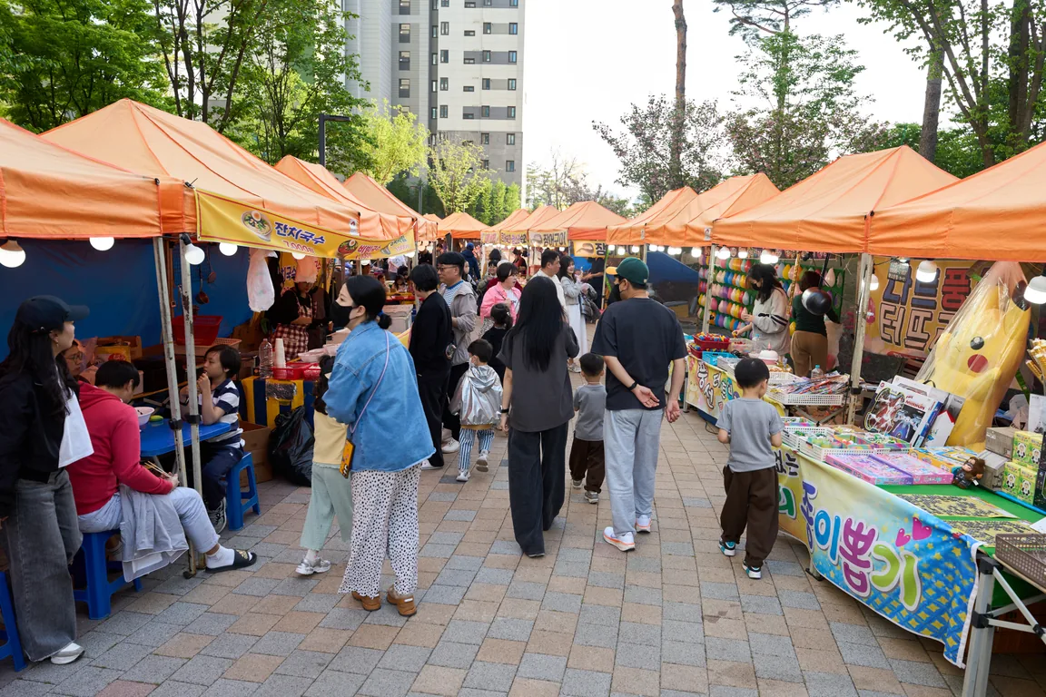 광장 통로에 한 줄로 늘어선 주황색 먹거리 부스 천막과 오가는 주민들
