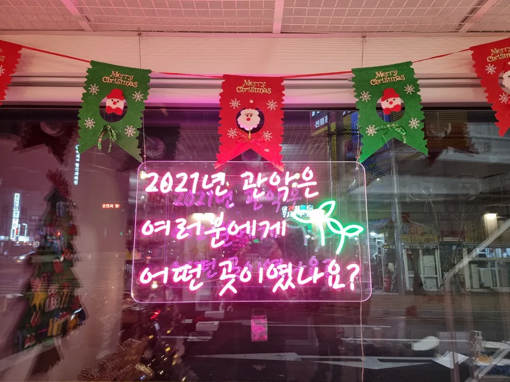 창에 걸린 분홍 네온 문구와 크리스마스 가랜드 장식