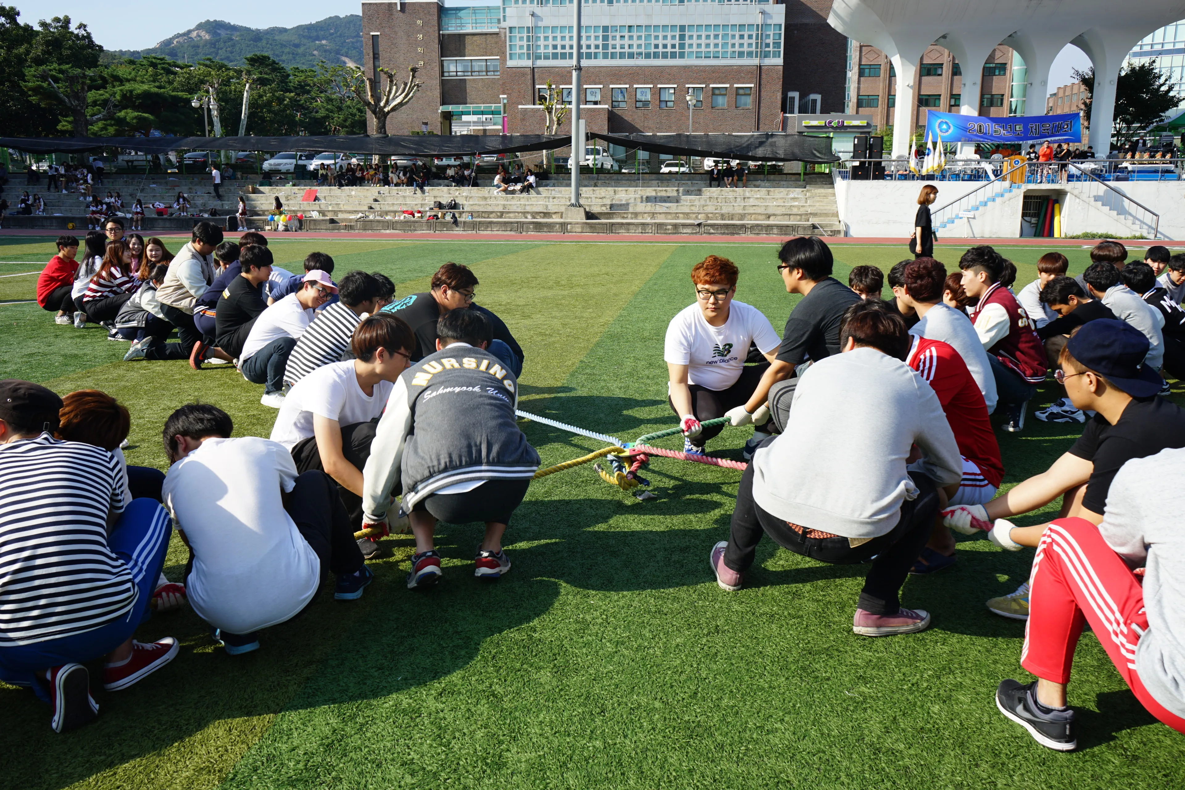 인조잔디 운동장에 웅크려 앉아 줄을 잡고 게임하는 학생들