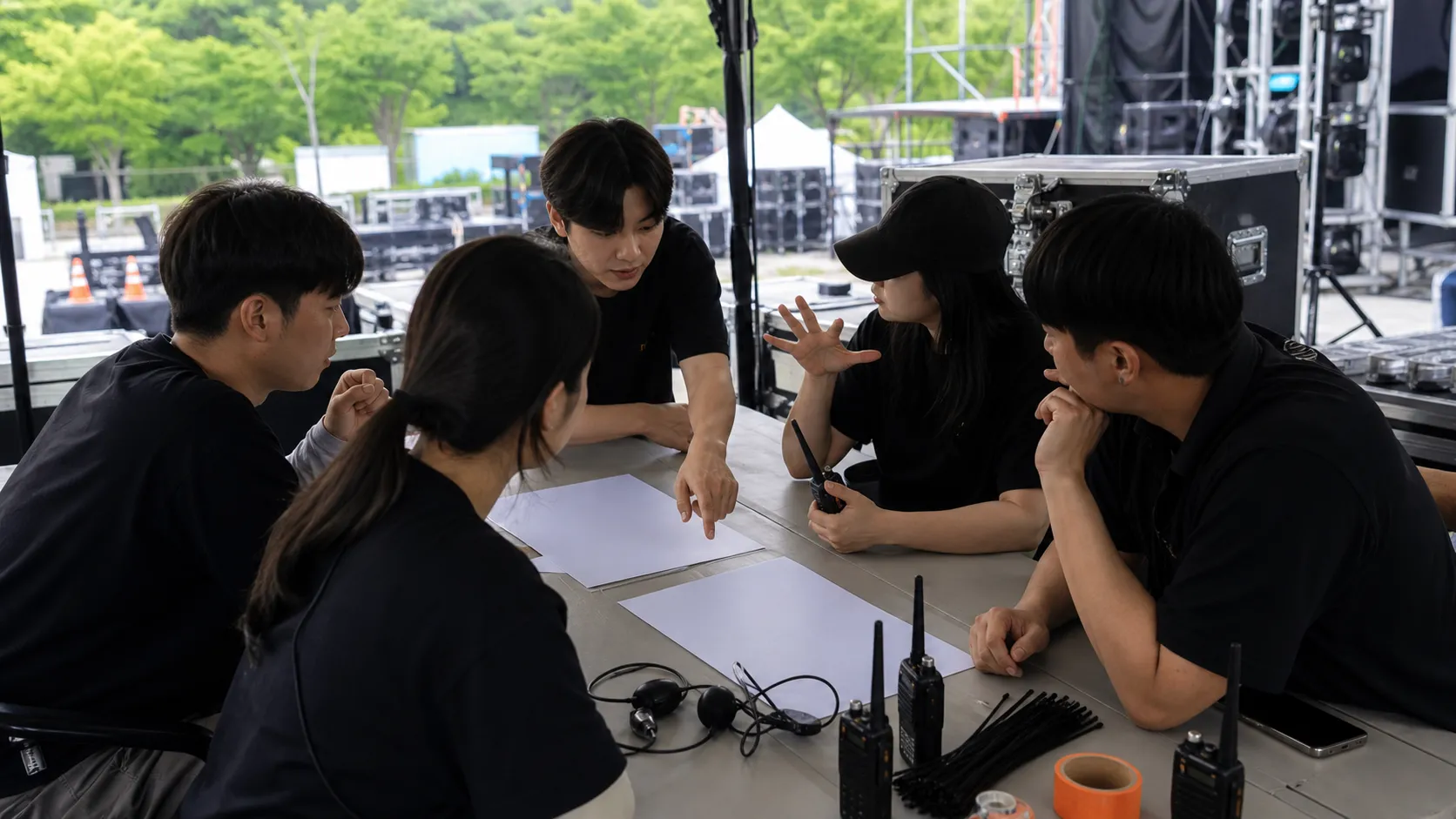 무대 설치 현장 테이블에서 서류를 놓고 회의하는 축제 운영 인력